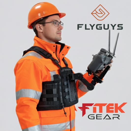 Person in orange safety gear holding a radio device with 'Flyguys' and 'Fitek Gear' branding.