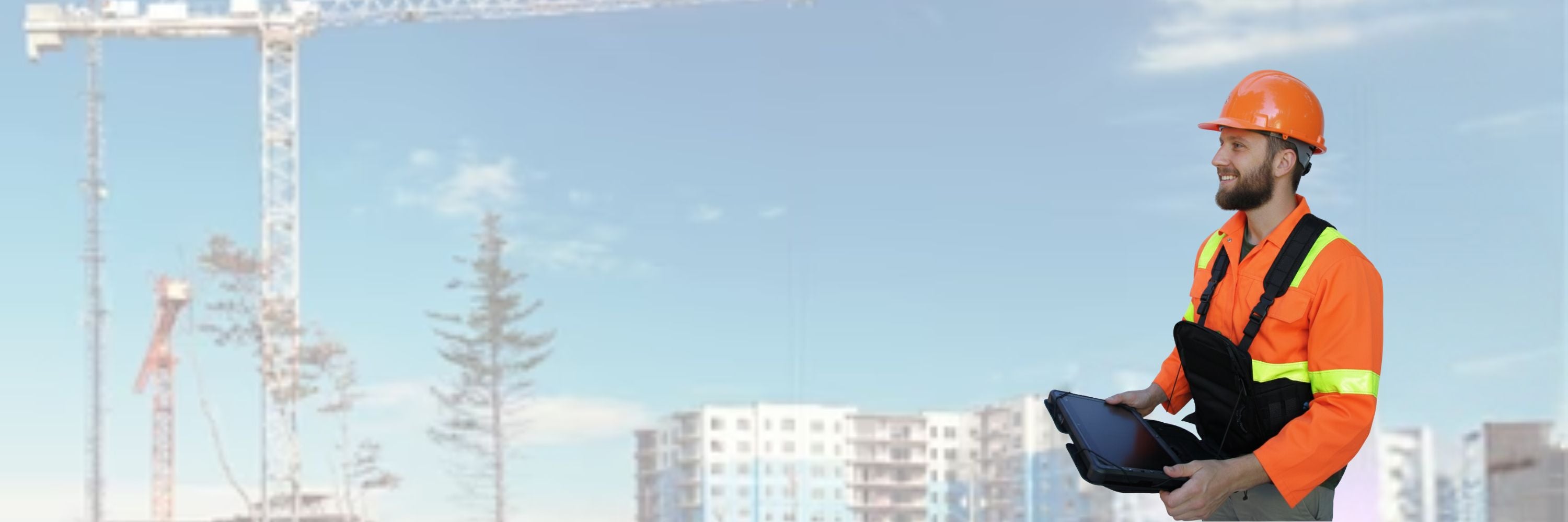 A professional in high-visibility safety gear and an orange hard hat operating a tablet for a drone site inspection at a commercial construction project with cranes in the background.